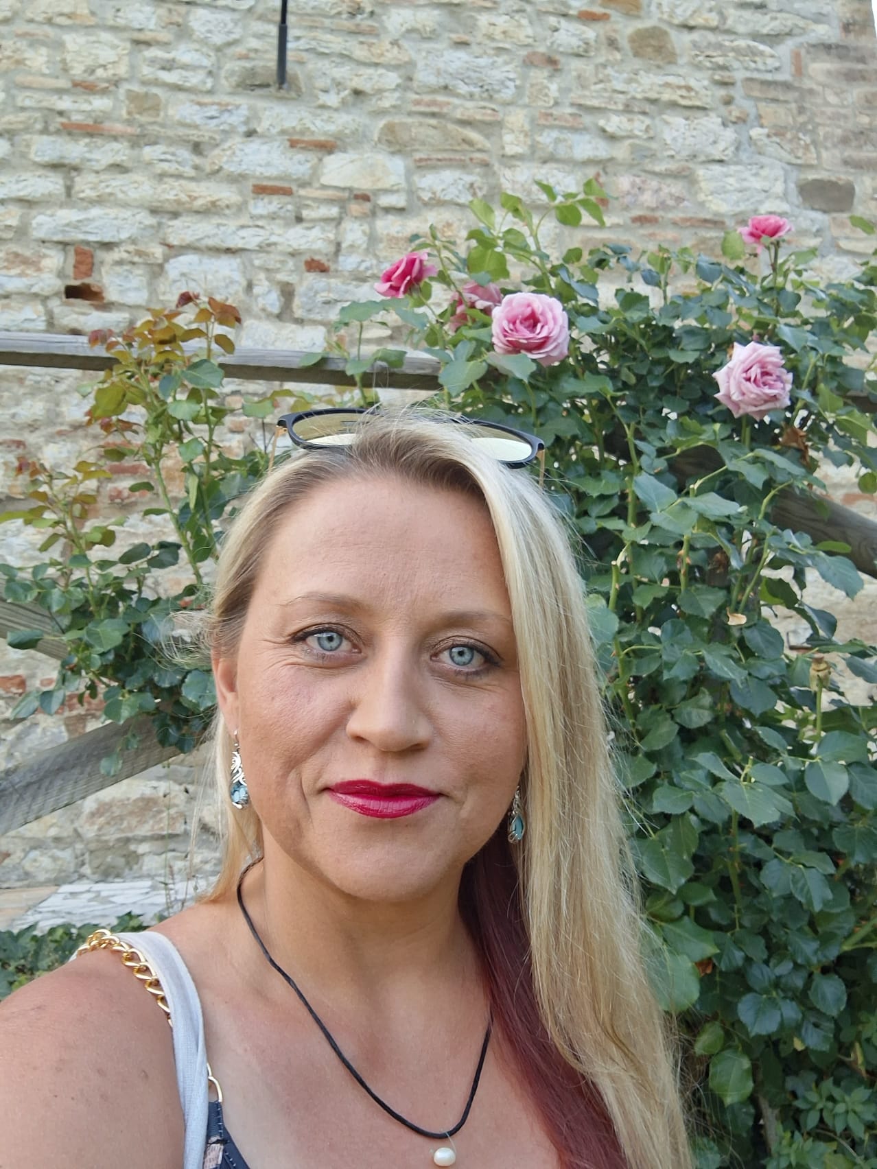 Pearl in front of roses and a stone wall.
